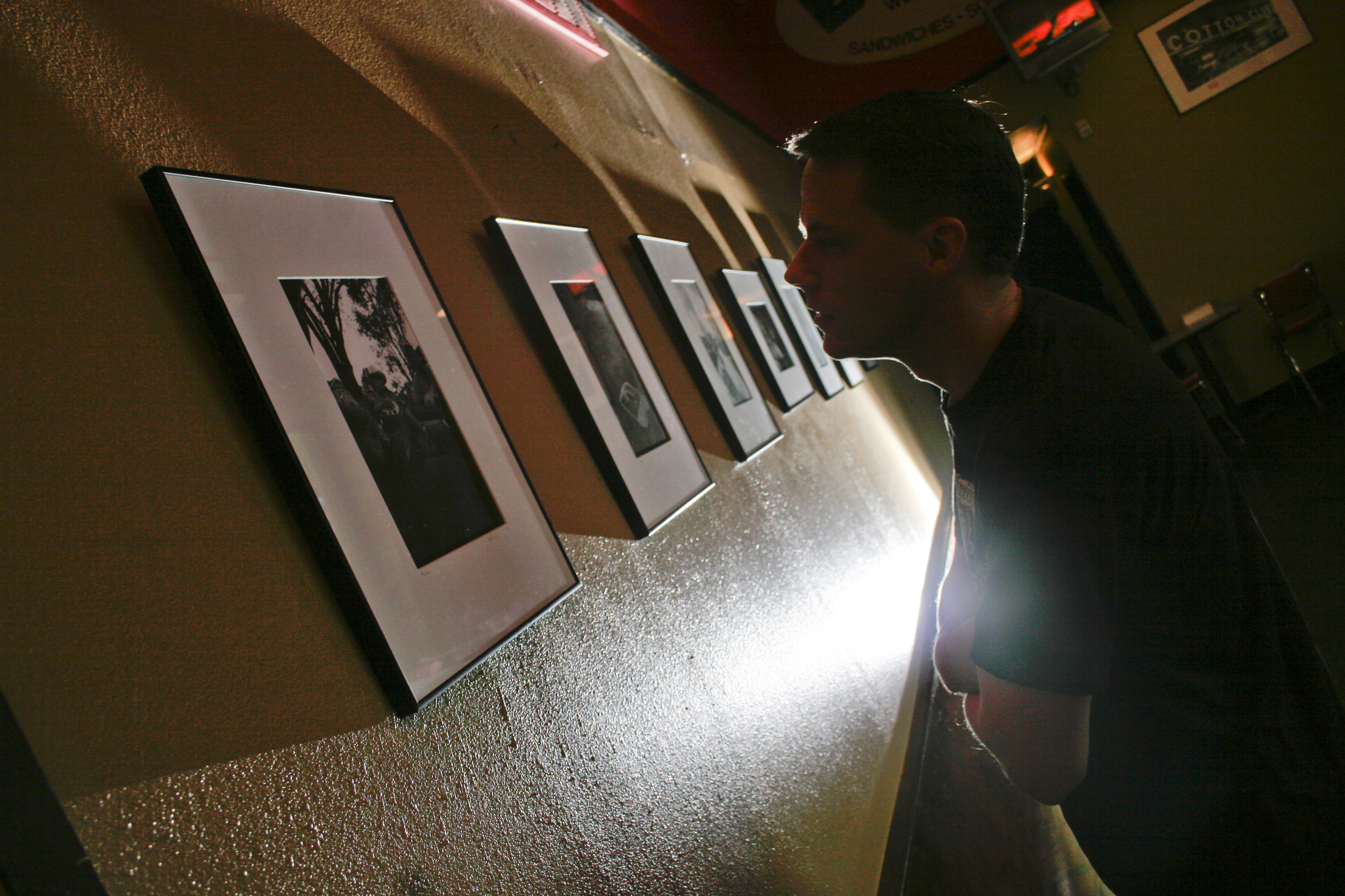 A diner at EJ's in downtown Little Rock stops to view photographs by John Bridges during a Thursday showing that also featured paintings by Stephano.