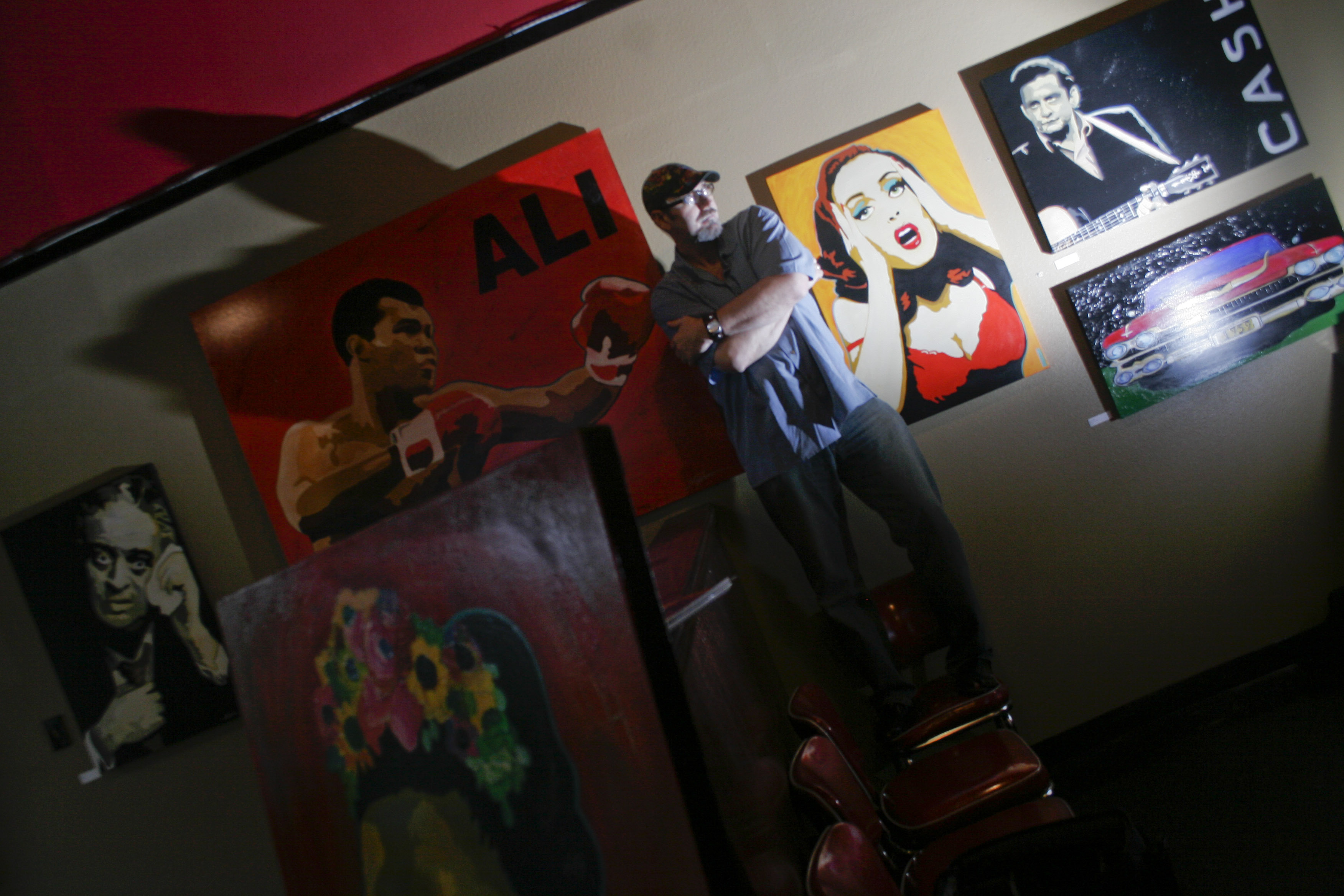 Little Rock artist Stephano stands near his paintings during a showing at diner at EJ's in downtown Little Rock Thursday that also featured photographs by John Bridges.