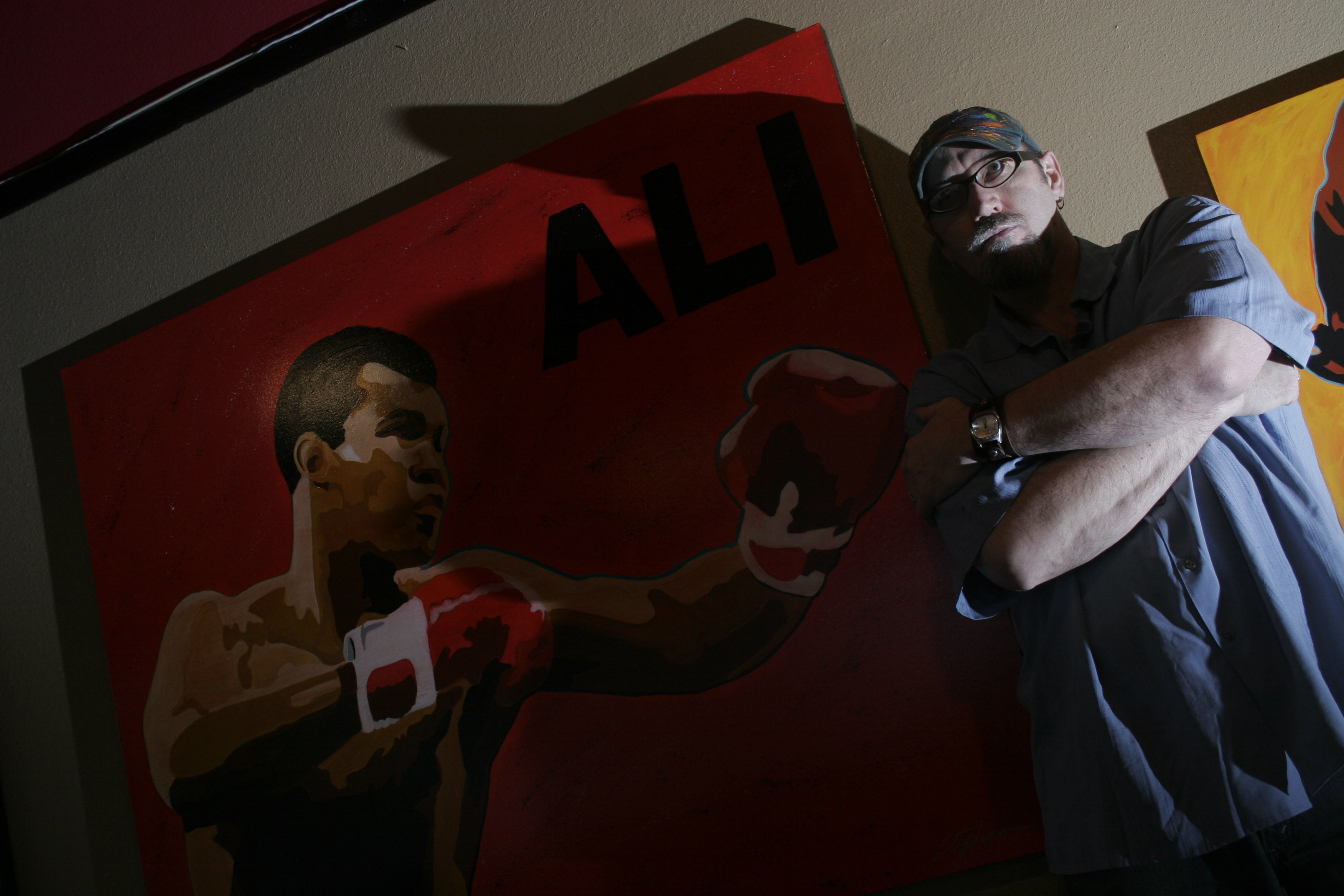 Little Rock artist Stephano stands near his paintings during a showing at diner at EJ's in downtown Little Rock Thursday that also featured photographs by John Bridges.