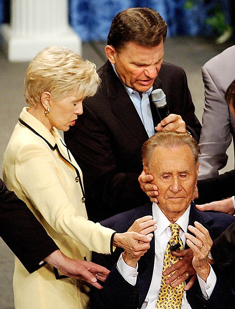 Televangelists Gloria Copeland and Kenneth Copeland lay hands on Oral Roberts, 85, during the International Charismatic Bible Ministries conference in the Mabee Center at Oral Roberts University in Tulsa in this 2003 file photo.