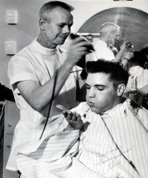 Elvis Presley has his hair cut by James Patterson at Fort Chaffee in March 1958.