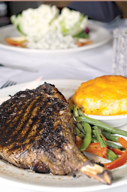 The Bone-in Cowboy Ribeye is served at Sonny Williams' Steak Room with au gratin potatoes and sauteed green beans.