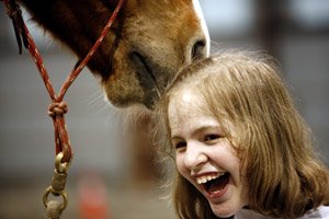 Jenny Thompson, 13, of Rogers laughs as Custer sniffs her hair Saturday at a ranch near Siloam Springs during a social-skills development group for autistic children.