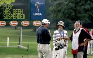 Golfer Anna Rawson (center) and her caddie are told of Saturday's weather delay by a tour official at the LPGA Northwest Arkansas Championship at Pinnacle Country Club in Rogers. More on weather problems on Page 8C.