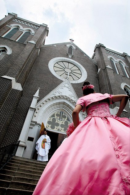 The Rev. Salvador Marquez-Munoz waits at the door to greet Brenda Flores, wearing a formal pink gown.