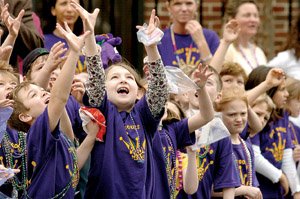 Katelyn McKinney (center) reaches up past Dominic Giangara, both students at Our Lady of the Holy Souls Catholic School, during a Mardi Gras parade held in front of the school in 2008.