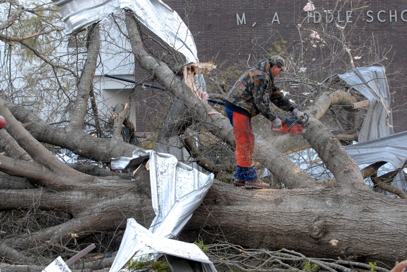 Workers clear down trees near the Polk County Courthouse in downtown Mena on Friday morning.  A tornado tore through Mena late Thursday night damaging or destroying much of downtown.