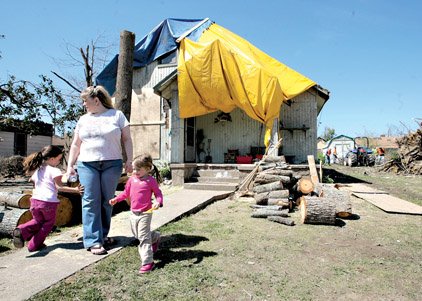 As a volunteer work crew clears debris from her storm-hit backyard Tuesday in Mena, Lisa Parsons tends to her granddaughter, Hailey Emerson, 3, (right) and neighbor Destiny Messinger, 4.

