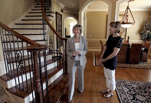 Sherry Hardie (left) with Harris McHaney Realtors shows Sandra Webb of Bentonville a home Thursday on Princeton Square in Bentonville. Home sales were down 21 percent in Benton County in March.