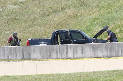 An investigator recovers a weapon Monday from a vehicle suspected of being used in a shooting at a military recruiting office Monday.