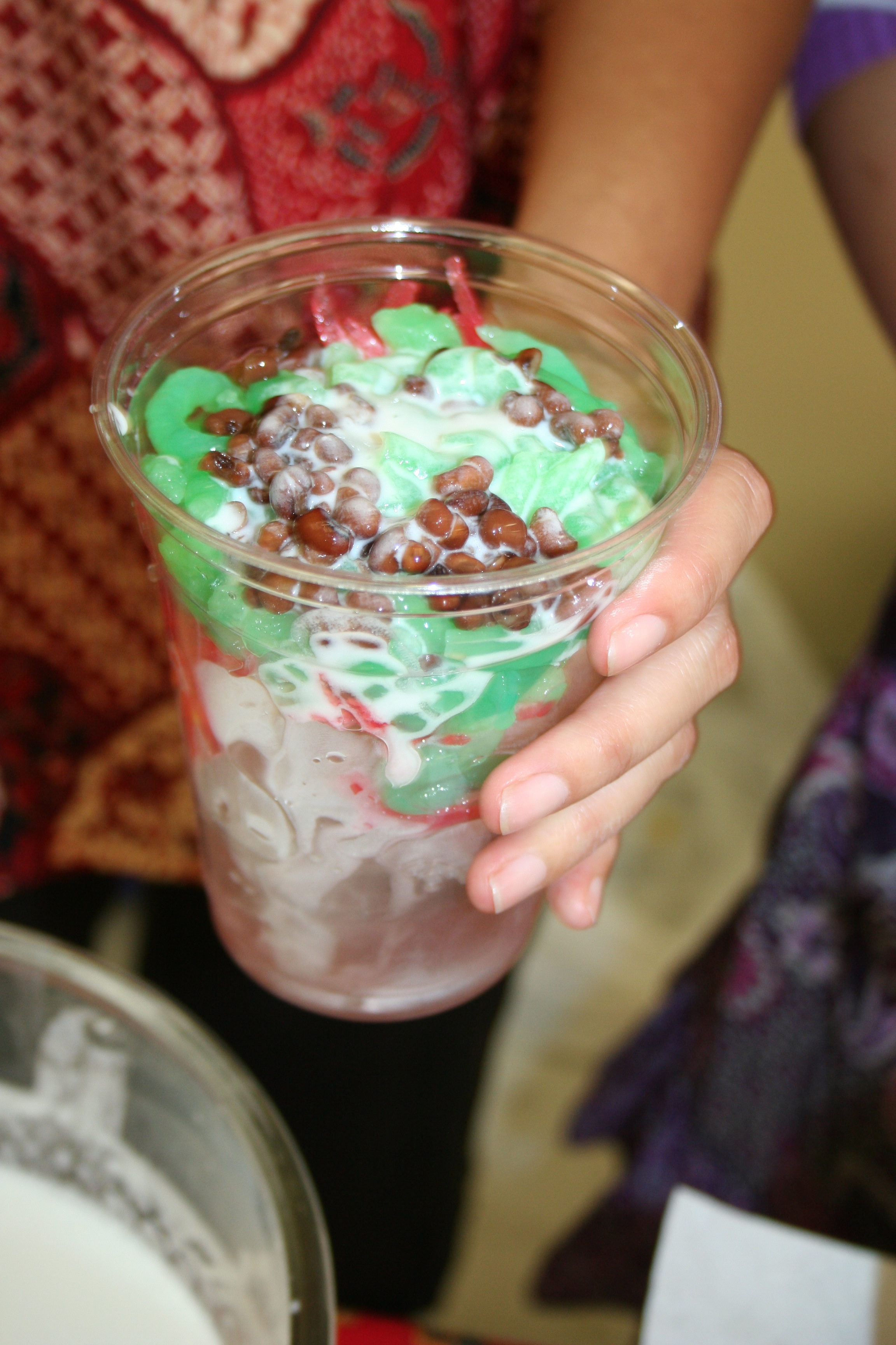 Ice Cendol: an iced drink with syrup, a Jello type substance (the bright green and orange), beans, coconut milk and fruit.