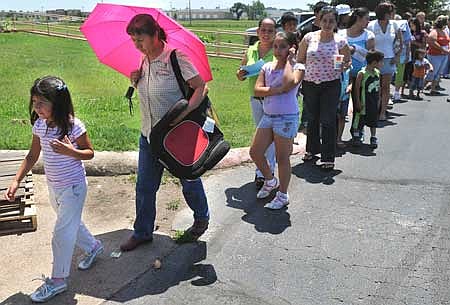 Guadalupe Rios, 5, of Rogers, left, and Maria Gonzalez waited in line Monday to receive free backpacks and school supplies at the Samaritan Community Center in Rogers. The center teamed up with the United Way to give away the backpacks and offer physicals, dental exams and back-to-school haircuts to local children in need. 