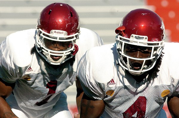 Universituy of Arkansas defensive backs Rudell Crim (right) and Anthony Leon (left) stretch out before the start of practice Wednesday afternoon at Razorback Stadium in Fayetteville.