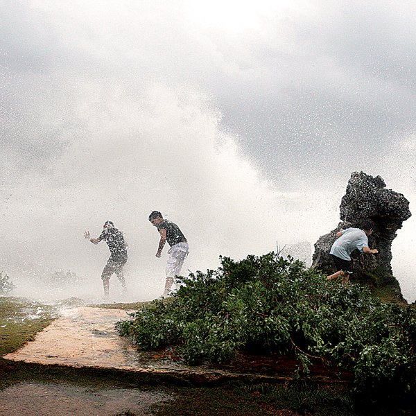 Youngsters move close to waves crashing on the rocks of Bermuda's Southshore area Saturday as Hurricane Bill passes. After skirting Bermuda early Saturday, the storm prompted officials in New England to urge caution as it moves northward.