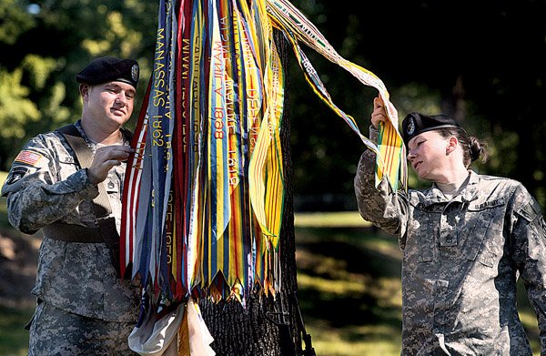 Staff Sgt. James Johnson (left) and Staff Sgt. April Evare admire the campaign ribbons for the 90th Regional Readiness Command with the Army Reserve before an inactivation ceremony at Camp Pike in North Little Rock on Saturday. 