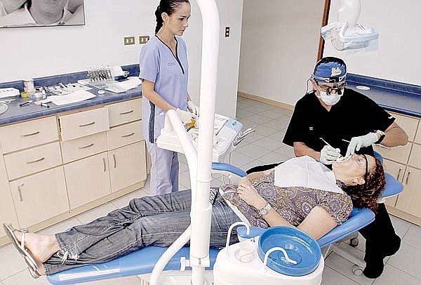 Dr. Alberto Meza, a dentist, applies cosmetic veneers on Alison Battle at Meza Dental Care in San Jose, Costa Rica.