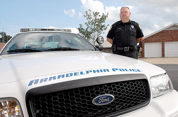 Cpl. Robert Jones with the Arkadelphia Police Department stands near one of the agency's Ford Crown Victoria patrol cars, which will soon be largely replaced with hybrid Toyota Camrys.