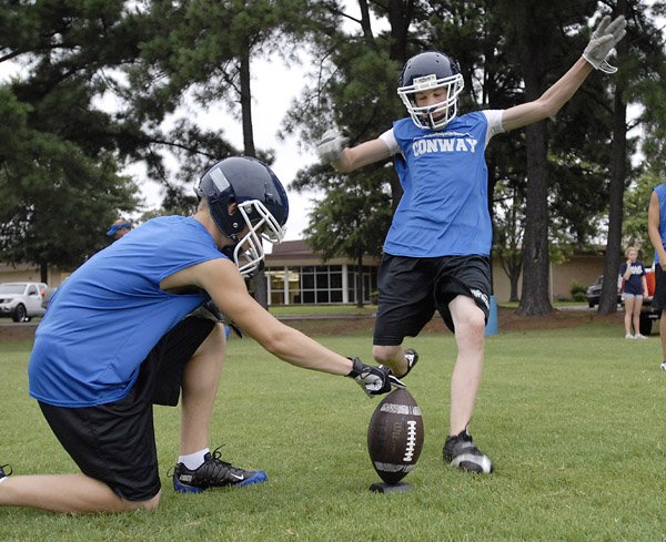 D.J. Alven holds the ball for Shane Holloway as he practices kicking. 