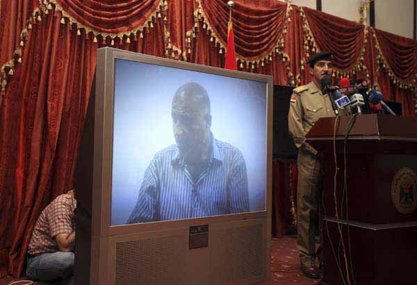 Maj. Gen. Qassim al-Moussawi (right), chief military spokesman for Baghdad, presents a videotaped confession of a Sunni man, seen on the screen and identified as the mastermind of one of two suicide bombings targeting government buildings, for reporters Sunday.