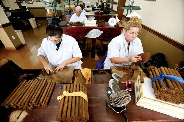 Odalis Fonseca (left) and Marta Diaz apply wrappers to cigars at a cigar factory in Miami's Little Havana neighborhood earlier this month.