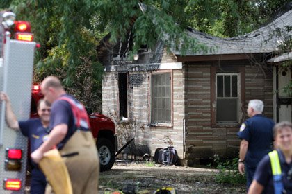  The burned-out house at 2508 S. Summit St. can be seen in the background as Little Rock firefighters gather up their firehoses after battling a houe fire across the street at 2517 S. Summit St. Saturday morning