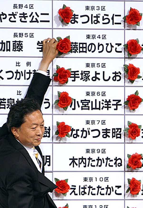 Yukio Hatoyama, president of the Democratic Party of Japan, places a red paper rose next to a Democratic candidate's name to indicate a victory at the party's election center Sunday in Tokyo.