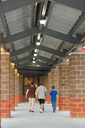 Parents and students walk along a covered corridor connecting the main academic building to a gym during Cabot Junior High North's open house.