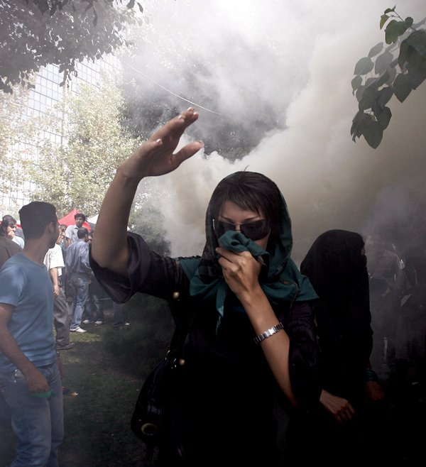 An Iranian opposition supporter (above) walks through a cloud of tear gas Friday during a demonstration in Tehran. 