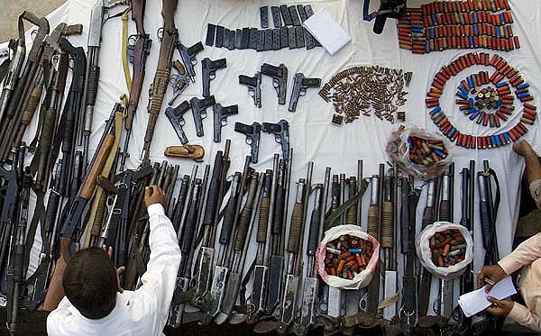 A Pakistani police officer sorts weapons confiscated from a private
security firm during a raid Saturday in Islamabad.