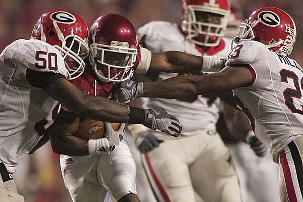 Arkansas running back Michael Smith is dragged down by Georgia's Darryl Gamble (50) and Prince Miller (23) in the Bulldogs' 52-41 victory at Reynolds Razorback Stadium in Fayetteville on Saturday. 