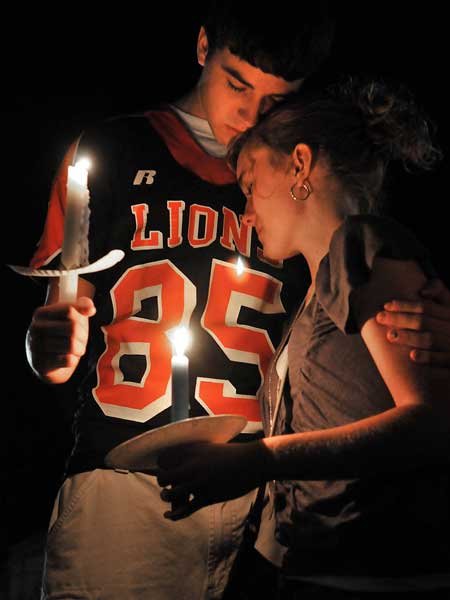 Brandon Meek and Holly Wells comforted each other while they paid their respects Wednesday evening at a candlelight vigil for Gravette football player Casey Russell, who died Wednesday morning. 