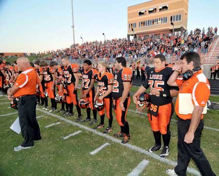 Gravette head coach Bill Harrelson, right, wiped tears from his face after a moment of silence in memory of Casey Russell before Friday night's game against Pea Ridge at Lion Stadium in Gravette. 