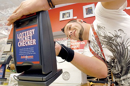 Sage Sanger of Intralot Inc. installs a lottery ticket checker Friday at the Sufficient Grounds Metro eatery in downtown Little Rock.
