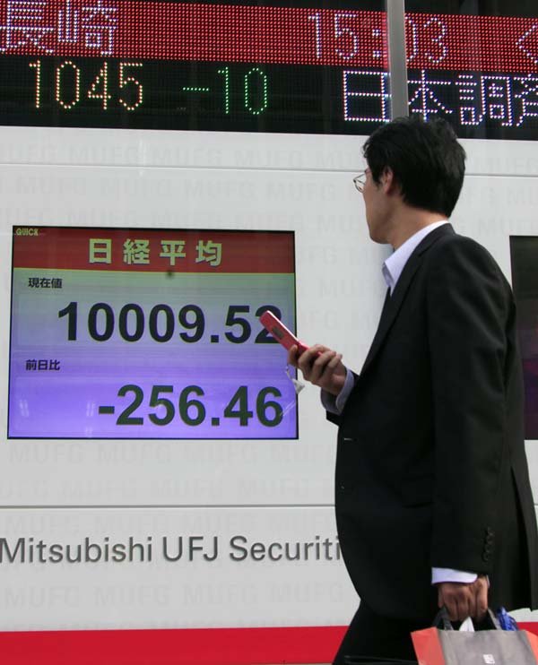 A businessman watches an electronic display showing Monday's closing price of the Nikkei 225 index at the Tokyo Stock Exchange in Tokyo.