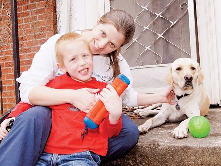 Christy Etters, her 6-year-old son, Jackson, and his dog, Chester, take a break on the steps of their home in Conway. The autism service dog, which cost $13,500, was purchased in Oregon. A Conway man whose son also is autistic helped lead fundraising efforts.