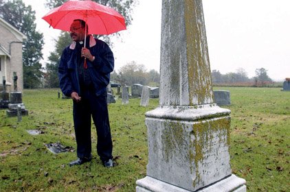 The Rev. Warren Harvey, pastor of St. Joseph Catholic Church in Pine Bluff, stands next to the headstone of Sister Agnes Hart, whom Harvey believes could be considered for sainthood.