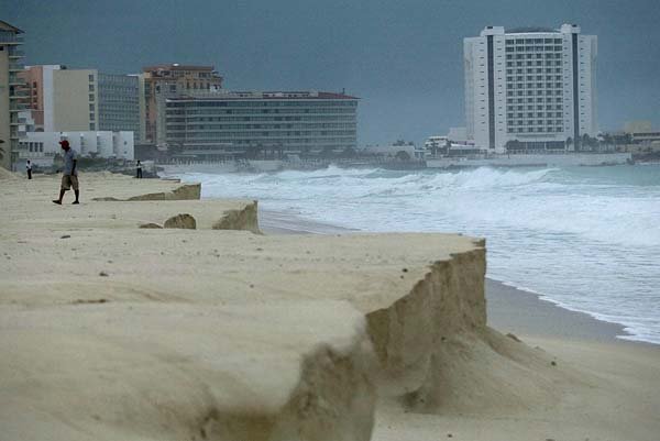 A man walks along a beach eroded from large waves after Hurricane Ida passed nearby Sunday in Cancun, Mexico.
