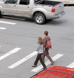 Pedestrians cross Spring Street at Sixth Street in downtown Little Rock on Monday.