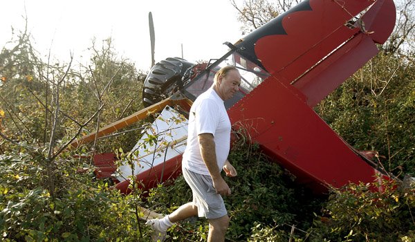 Siloam Springs Airport manager Michael Scroggin looks over a damaged plane Tuesday in a field off Waukesha Road.