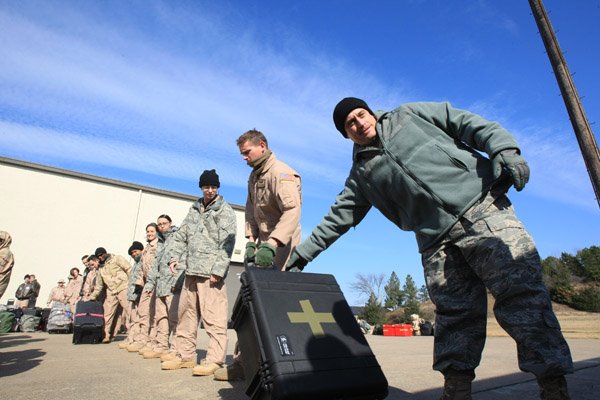 Lt. Col. Ken Kopp (right) passes a piece of luggage down the line as members of the 61st Airlift Squadron load gear in preparation for the unit’s deployment Wednesday from Little Rock Air Force Base in Jacksonville. 