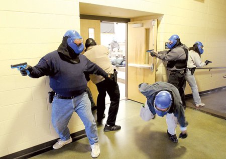 A “hostage” flees a room while law enforcement officers prepare to enter in a live shoot-out exercise Sunday at Barker Middle School in Bentonville.