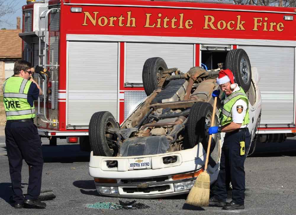 Arkansas Democrat-Gazette STATON BREIDENTHAL --122109-- Lt. Matt Matthews (left) and Capt. James Craig of the North Little Rock Fire Department clean up debris Monday at the scene of a two vehicle accident at the intersection of Riverfront Drive and Washington Ave. in North Little Rock. There were no injuries reported in the accident.