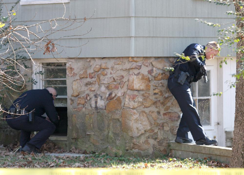 Arkansas Democrat-GazetteRICK MCFARLAND--122109-- A North Little Rock Police officer enters an open window and another covers the back door of the lower level of a home where a body was found at 4421 Augusta St., in North Little Rock Monday morning. It is being investigated as a possible homicide.