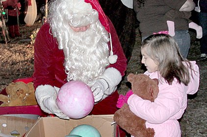 John Patrick, who has played Santa outside his Pocahontas home for 28 years, gives toys Sunday night to Lindsey Gazaway, 6.