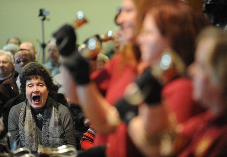 Felicia Stott of Fayetteville reacts with joy to the playing of a portion of Handel’s “Messiah” by members of Ozark Bronze, a select handbell choir, on Dec. 13 at the Fayetteville Public Library.