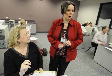 Ashley Daniel, right, data and accountability specialist for Rogers Public Schools, assists Amy Putnam, assistant principal of Westside Elementary School, and other district principals and teachers through the Learning Instruction progress reporting system Thursday during a data team meeting at The Annex in Rogers.
