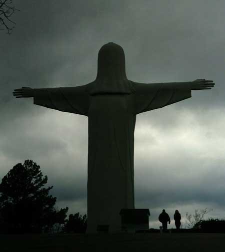 Visitors walk past the Christ of the Ozarks statue as rain clouds roll by Wednesday afternoon at the Great Passion Play grounds in Eureka Springs. Forecasters expect rain showers to change into snow this evening. 