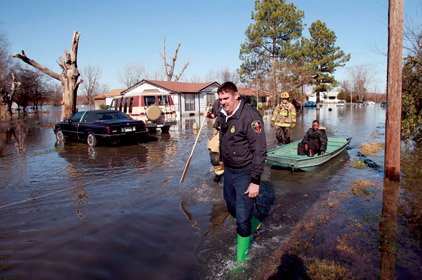 Larry Thurston, who has difficulty walking, is evacuated Saturday after he reported 2 feet of floodwater in his house on North G Street in the Dixie Addition of North Little Rock on Saturday. North Little Rock firefighters (left to right) Capt. Bo Buford, Michael Sanchez (hidden by Buford) and Greg Brown pulled the boat.