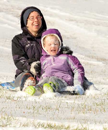 Chloe Cooper, 6, gets a face full of snow Friday while riding with Courtney Nixon in Bentonville. The two were sledding a popular hill along North Walton Boulevard.