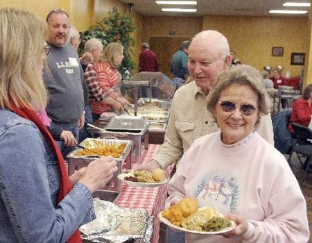 Jim and Rae Oden go through the serving line Friday for a Christmas dinner at the Central United Methodist Church in Rogers.